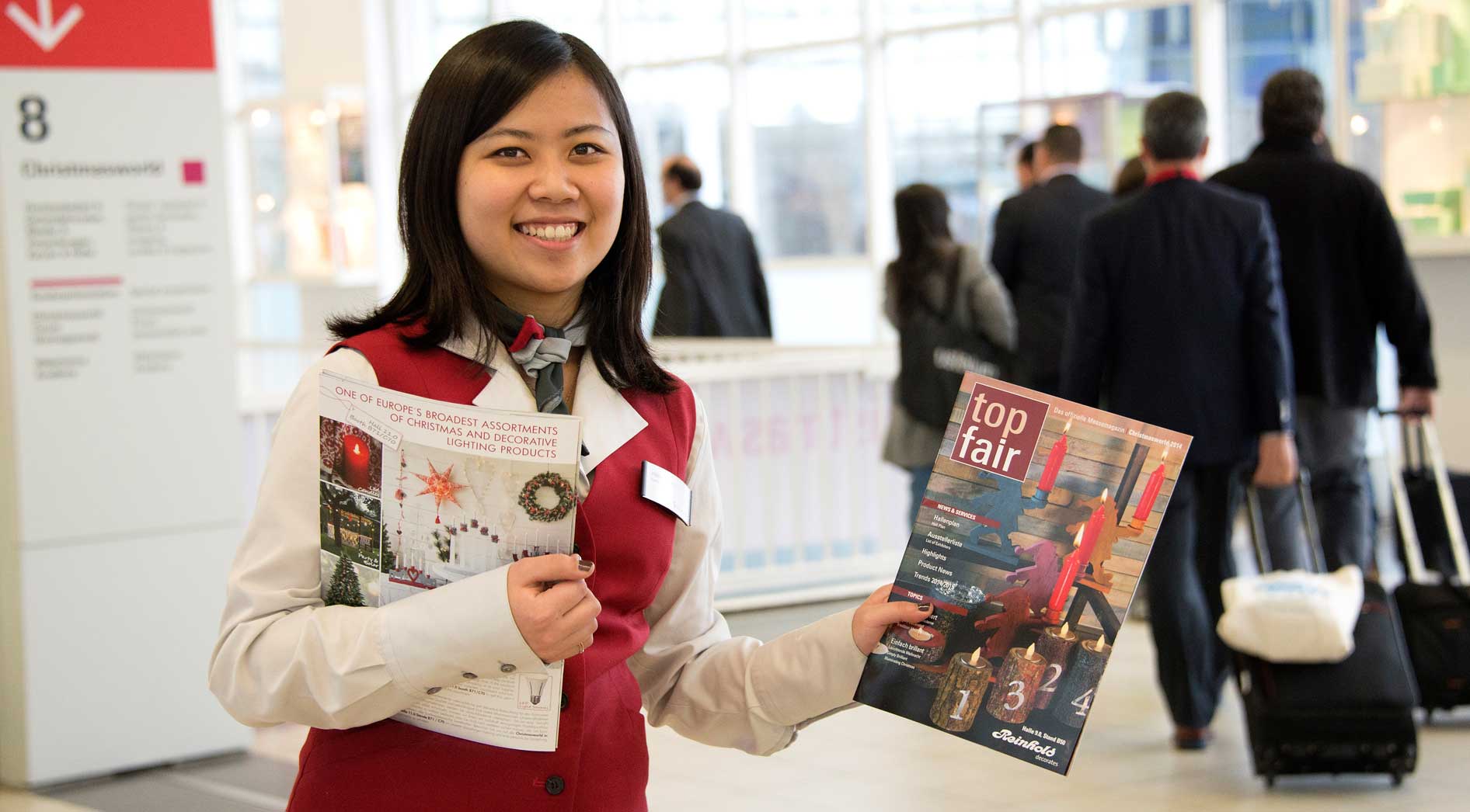 Hostess hält das Messemagazin "top fair" in der Hand